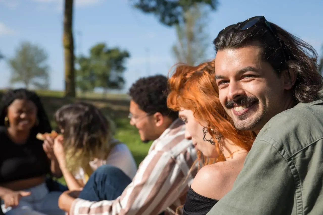 a-man-smiling-while-sitting-with-his-friends